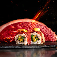 Piezas de sushi de fusión servidas sobre pizarra con chispas de brasa al fondo